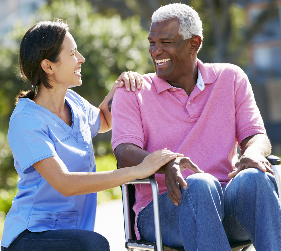Carer Pushing Senior Man In Wheelchair